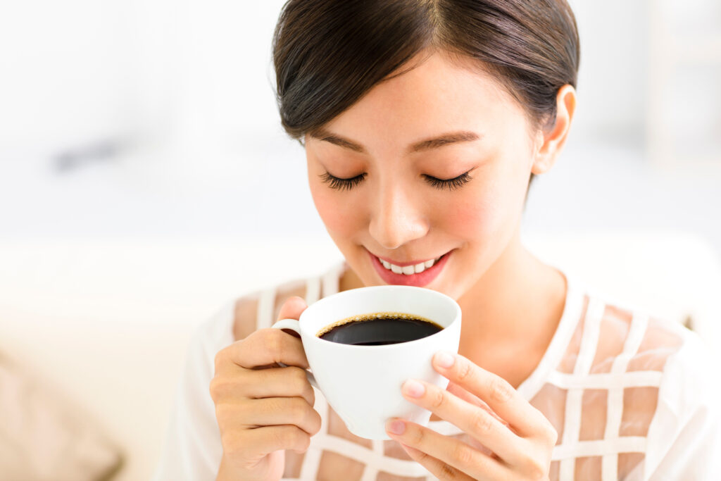 A woman enjoying a cup of coffee, showcasing her bright smile