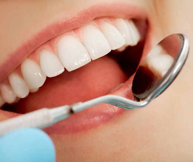 Dentist examining teeth with dental mirror – bad breath treatment