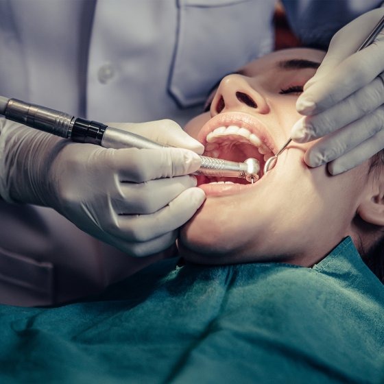 Dentist performing a root canal treatment on a patient using a dental handpiece and endodontic instruments.
