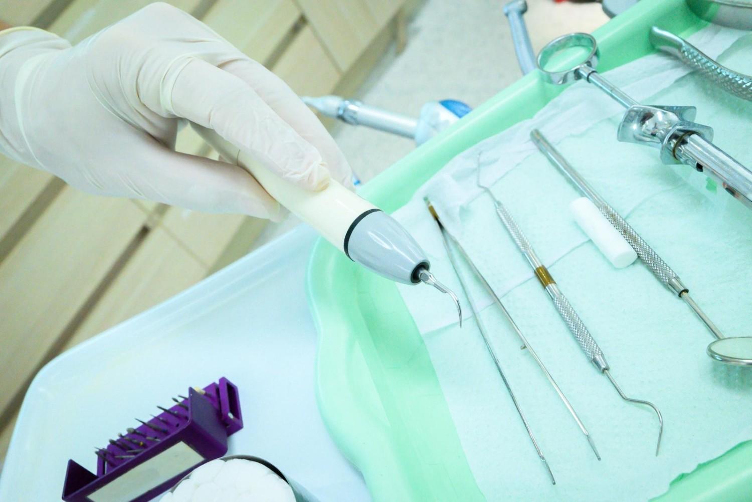 Image showing an ultrasonic scaling device and dental tools arranged for professional dental cleaning, featured in the article “What happens during dental cleaning.